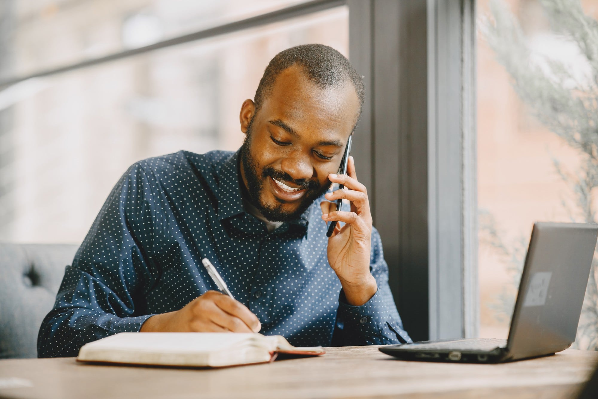 african-american-man-working-laptop-talking-phone-man-with-beard-sitting-cafe