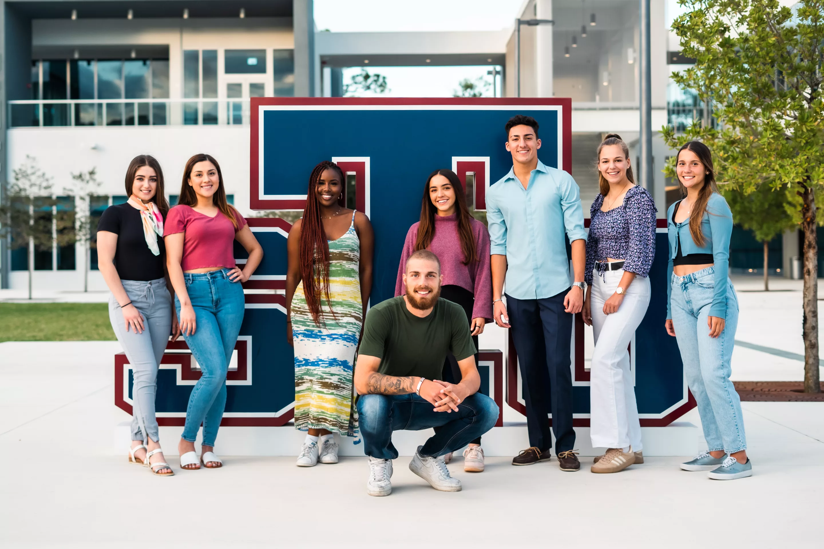 A group of students posing in front of Saint Thomas University.