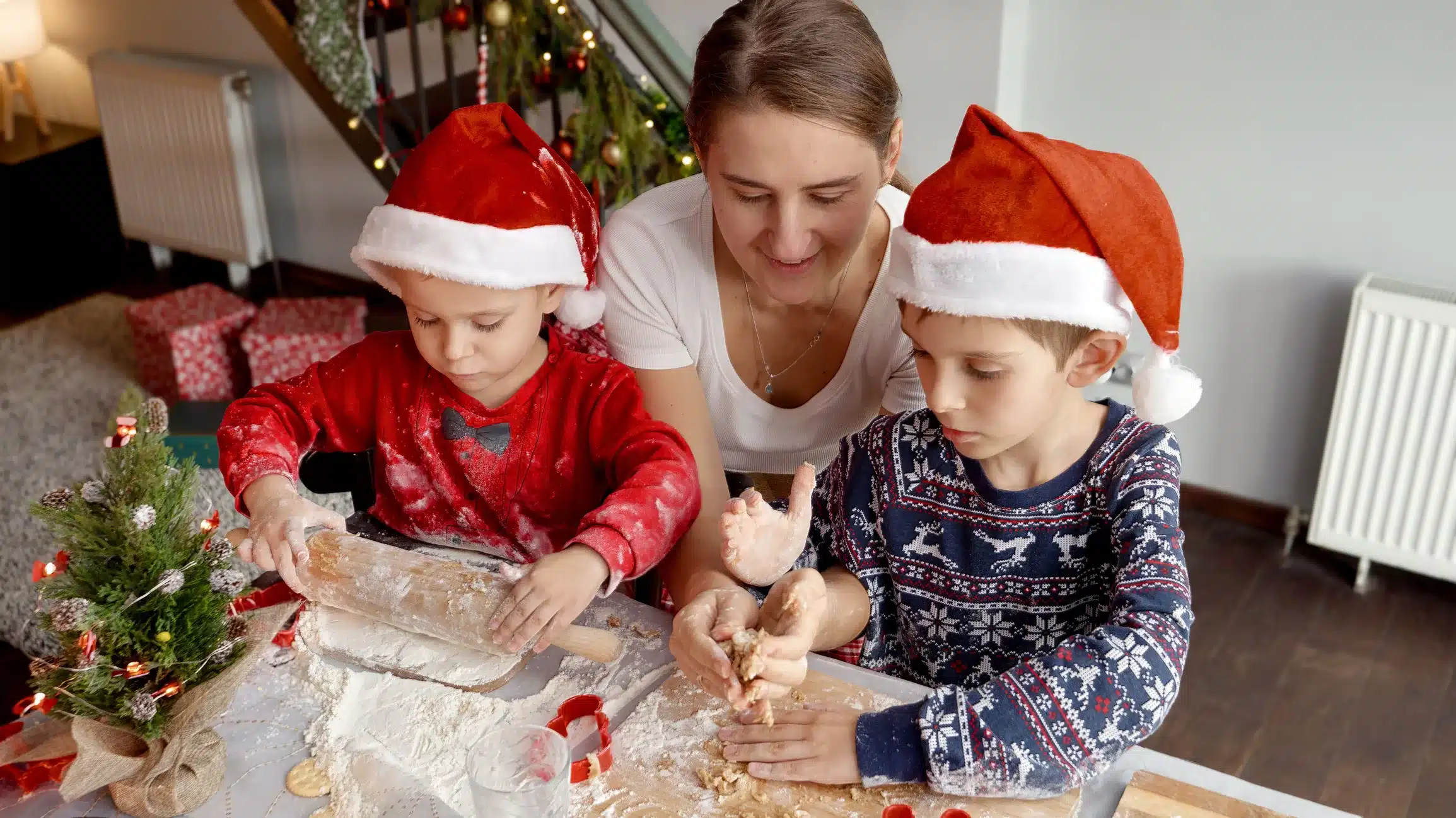 A mother and her two sons are baking Christmas cookies. Christmas 2023 is just around the corner and they're excited to spend it together.