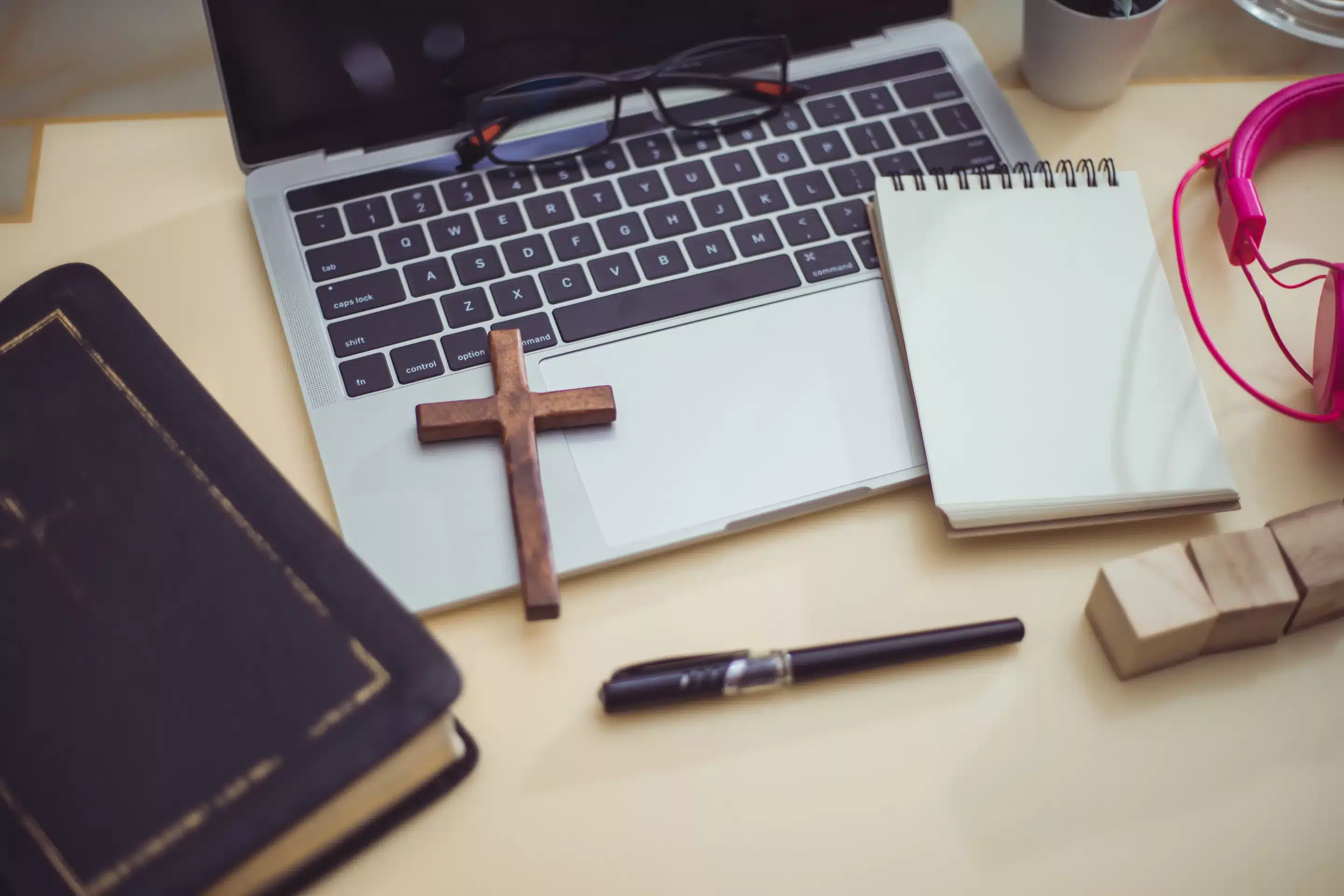 laptop on table next to books for christian online schools